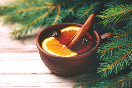 Hot mulled wine with orange, anise, cardamon and cinnamon on slate marble background. Christmas tree branches and cones. Flat lay, copy space, horizontal view. Holidays.の写真素材