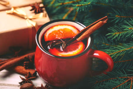 Hot mulled wine with orange, anise, cardamon and cinnamon on slate marble. Christmas tree branches, gifts and cones. Flat lay, copy space, horizontal view. Holidays.の写真素材