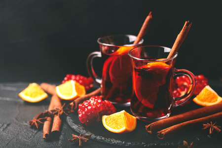 Hot mulled wine with apples, pomegranate, orange, anise and cinnamon with fresh fruits on slate marble background. Flat lay, copy space, horizontal view. Christmas and holidays foodの写真素材