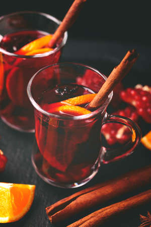 Hot mulled wine with apples, pomegranate, orange, anise and cinnamon with fresh fruits on slate marble background. Flat lay, copy space, top view. Christmas and holidays foodの写真素材