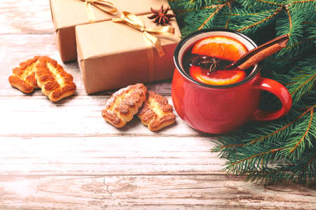 Hot mulled wine with spices and cookies on slate marble background. Christmas tree branches, gifts and cones. Flat lay, copy space, horizontal view. Holidays.の写真素材