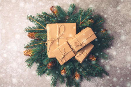 Christmas background. Craft gift boxes and decoration - Christmas tree branches and cones on slate...