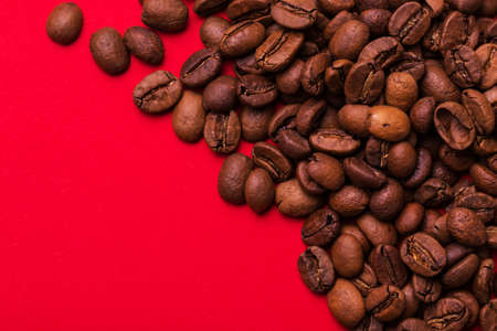 Roasted coffee beans isolated on red background. Color surge trend. Macro