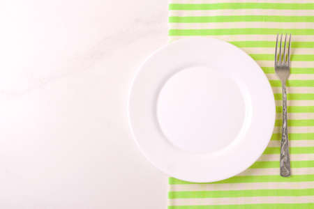 Food background. White empty plate, cutlery, napkin on stone gray background. Top view, flatlay, copyspace.の写真素材