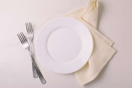 Food background. White empty plate, cutlery, napkin on stone gray background. Top view, flatlay, copyspace.の写真素材