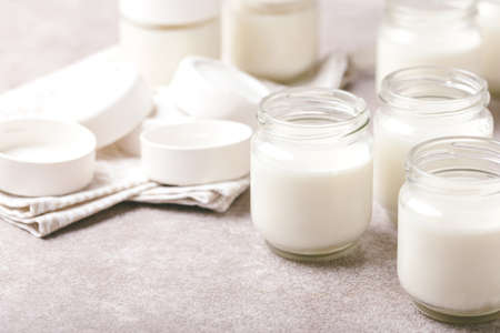 Homemade greek yogurt in glass jars and yogurt maker on gray stone background. Healthy food conceptの写真素材