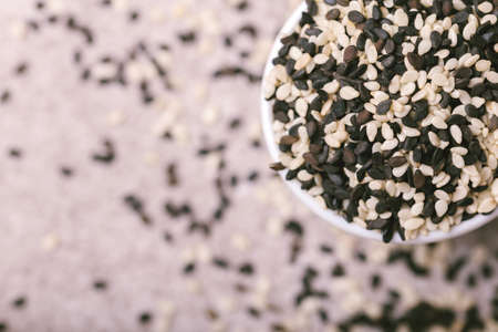 Black and white sesame seeds in bowls on gray stone background. Copy space. Top view.の写真素材