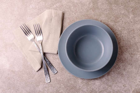 Food background. White empty grey plate and bowl, cutlery, napkin on stone gray background. Top view, flatlay, copyspace.の写真素材
