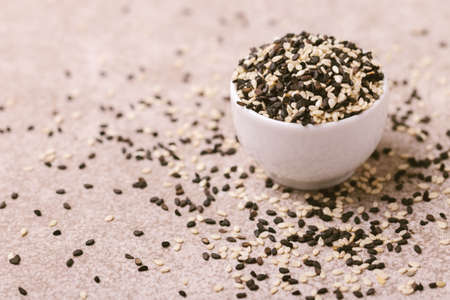 Black and white sesame seeds in bowls on gray stone background. Copy space. Horizontal view.の写真素材