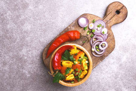 Indian cuisine. Paneer Tikka Kabab with chilli pepper, onions and curry sauce on grey stone background. Asian salad. Top view. Copy spaceの写真素材