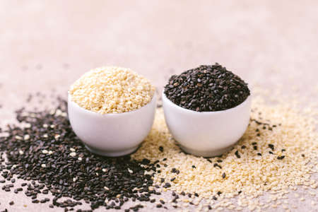 Black and white sesame seeds in bowls on gray stone background. Copy space. Horizontal view.の写真素材