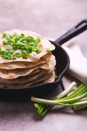 Traditional Kerala Indian cuisine. Homemade flatbread chapati with green onion on gray slate background. Copyspace, horizontal view, flatlay. Color surge trend.の写真素材