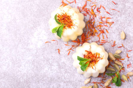 Traditional Rajasthani Indian cuisine. Homemade kulfi dessert, ice cream with safron, mint and nuts on gray slate background. Copyspace, top view.の写真素材