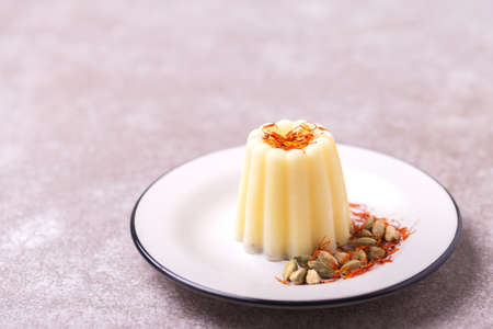 Traditional Rajasthani Indian cuisine. Homemade kulfi dessert, ice cream with safron, mint and nuts on gray slate background. Copyspace, horizontal view.の写真素材