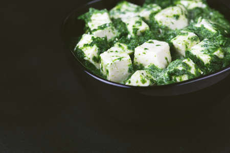 Traditional Indian cuisine. Homemade palak paneer on black slate background. Copyspace, horizontal...