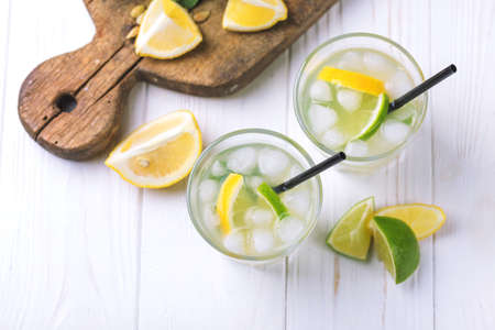 Tradtitional Italian homemade lemon and lime liqueur limoncello with ice and mint on wooden background. Alcoholic beverage. Selective focus.の写真素材