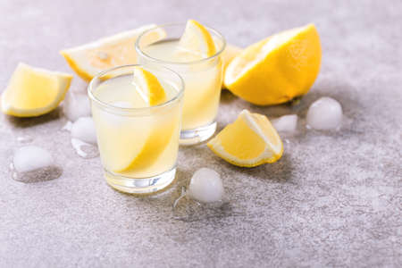 Tradtitional Italian homemade lemon and lime liqueur limoncello with ice and mint on gray slate background. Alcoholic beverage. Selective focus.の写真素材