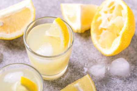 Tradtitional Italian homemade lemon and lime liqueur limoncello with ice and mint on gray slate background. Alcoholic beverage. Selective focus.の写真素材