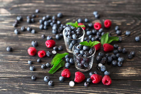 Blueberries, raspberries and mint at black wooden table. Summer organic berry. Agriculture, Gardening, Harvest Conceptの写真素材