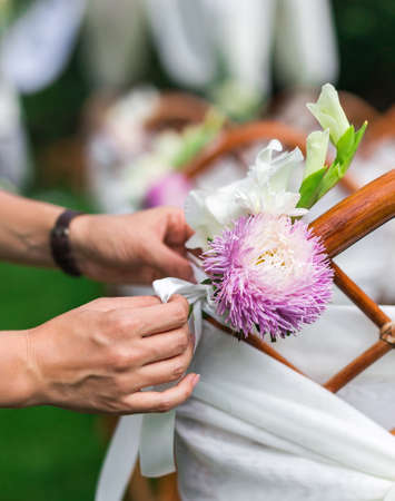 Decorator working with flowers composition for chairs. Wedding concept. Close up.の写真素材