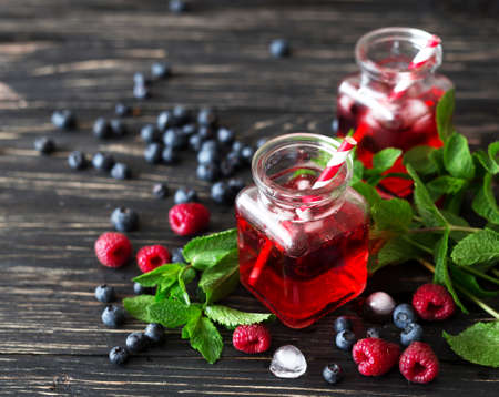Fresh cocktail with blueberry, raspberry, mint and ice.  Black wooden tableの写真素材