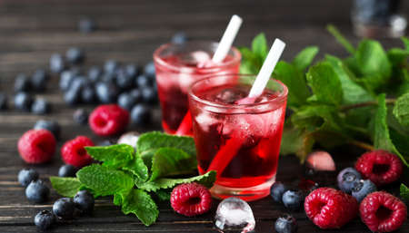 Fresh cocktail with blueberry, raspberry, mint and ice. Selective focus. Black wooden tableの写真素材