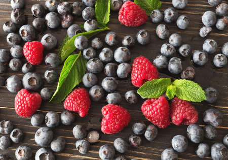 Blueberries, raspberries and mint at black wooden table. Summer organic berry. Agriculture, Gardening, Harvest Conceptの写真素材