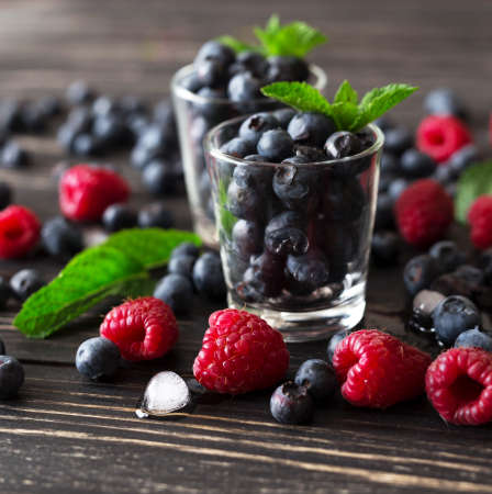Blueberries, raspberries and mint at black wooden table. Summer organic berry. Agriculture, Gardening, Harvest Conceptの写真素材