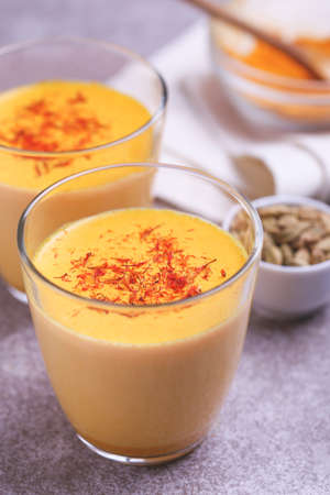 Traditional Indian cuisine. Turmeric milk with cinnamon, saffron, cardamom and turmeric on gray slate background. Copyspace, top view, flatlayの写真素材