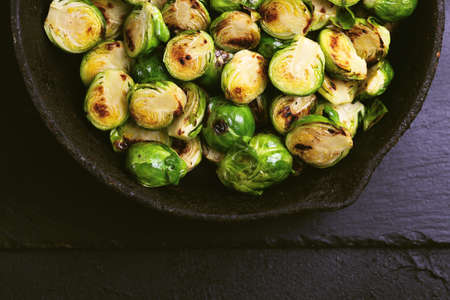 Vegetarian cuisine. Homemade Brussels Sprouts roasted with olive oil on black slate background. Copyspace, top view, flatlay.の写真素材