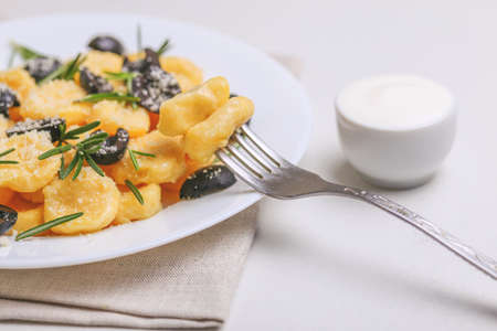 Traditional Italian cuisine. Gnocchi with a cream sauce, olives and rosemary on white background. Copyspace, horizontal viewの写真素材