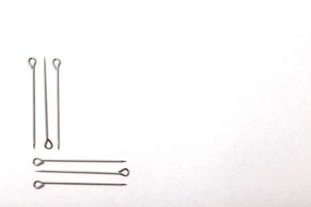 Silver sewing pins on white studio background. Top view, flat layの写真素材