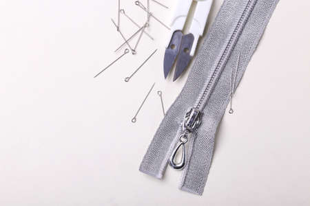 Silver sewing pins, scissors, zipper on white studio backgroundの写真素材