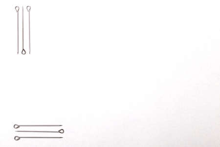 Silver sewing pins on white studio background. Top view, flat layの写真素材