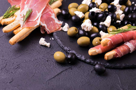 Traditional italian bread sticks grissini with prosciutto ham on a plate, top view