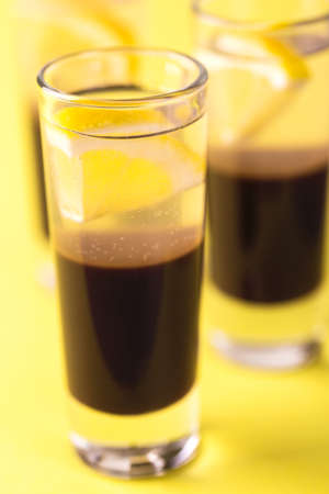 Alcoholic shot cocktail silver bullet with gin, coffee chocolate liqueur and lemon. Yellow...