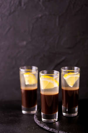 Alcoholic shot cocktail silver bullet with gin, coffee chocolate liqueur and lemon. Black...