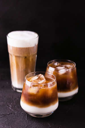 Iced coffee in glasses with milk and cream. Black background. Horizontal view. Copy space