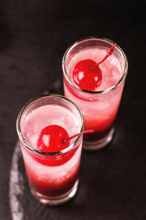 Alcoholic shot cocktail sour cherry gin or porch crawler with liqueur and lime. Black background....