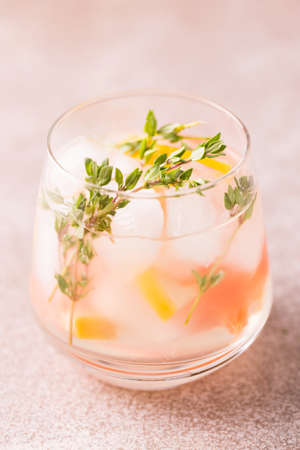 Alcoholic cocktail gin bitter lemon with thyme and grapefruit. Fruit lemonade. Gray slate background. Vertical view. Copy spaceの写真素材