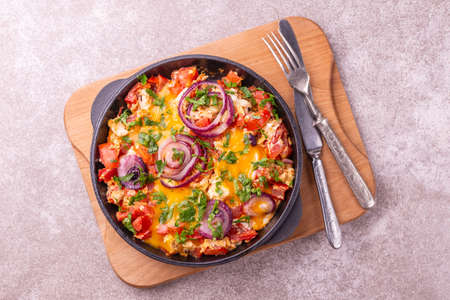 Shakshuka with bread toasts in a pan. Middle eastern and jewish traditional cuisine. Fried eggs with tomatoes, bell pepper, garlic, onion, vegetables and herbs.の写真素材