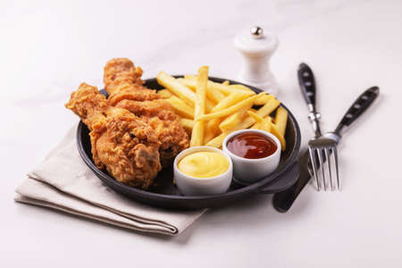 Fried crispy and spicy chicken legs and french fries potatoes with sauces. Fast and junk food concept. Top view, copyspaceの写真素材