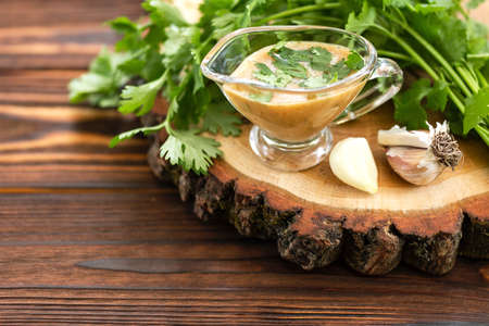 Sweet and sour sauce with herbs and garlic on the wooden background. Copyspace. Horizontal viewの写真素材