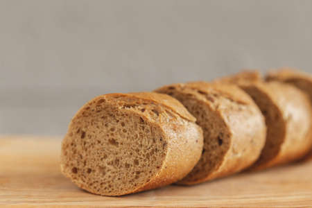 Fresh sliced rye baguette on the wooden cutting board. Horizontal view. Closeup. Copyspace