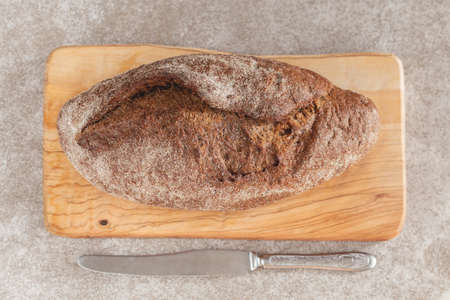 Fresh loaf of rye bread on the wooden cutting board background. Copysapace
