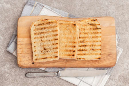 Crispy toasts for breakfast on the grey slate background with knife and napkin. Top view