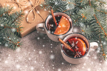 Hot mulled wine in a small vintage cups with christmas tree and present with snowy effect. Christmas or winter warming drink. Horizontal view. Copy spaceの写真素材