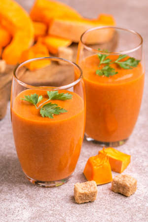 Fresh pumpkin smoothie in tumbler with parsley on gray slate background. Horizontal view. Copy spaceの写真素材