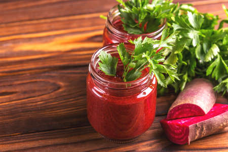 Bright beetroot smoothie in jar with fresh pieces of beet and parsley on rustic wooden background. Horizontal view. Copy spaceの写真素材
