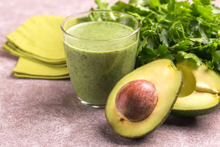 Fresh avocado smoothie in glass with parsley on marble gray background. Horizontal view. Copy space
